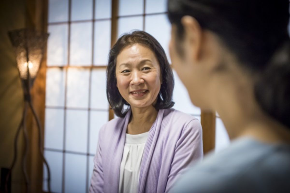 Asian patient conversing and smiling with doctor.